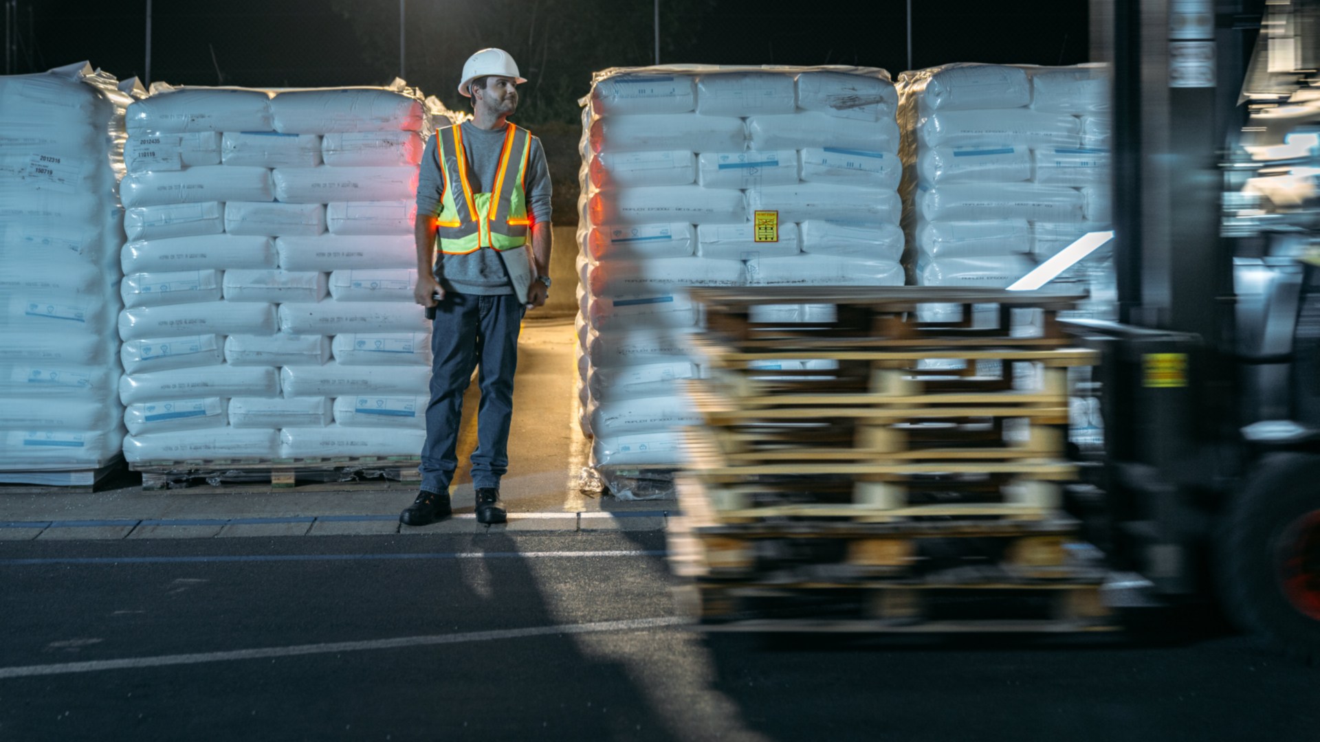 Un empleado del almacén y una carretilla se cruzan y el empleado es claramente visible gracias al chaleco reflectante interactivo de Linde Material Handling