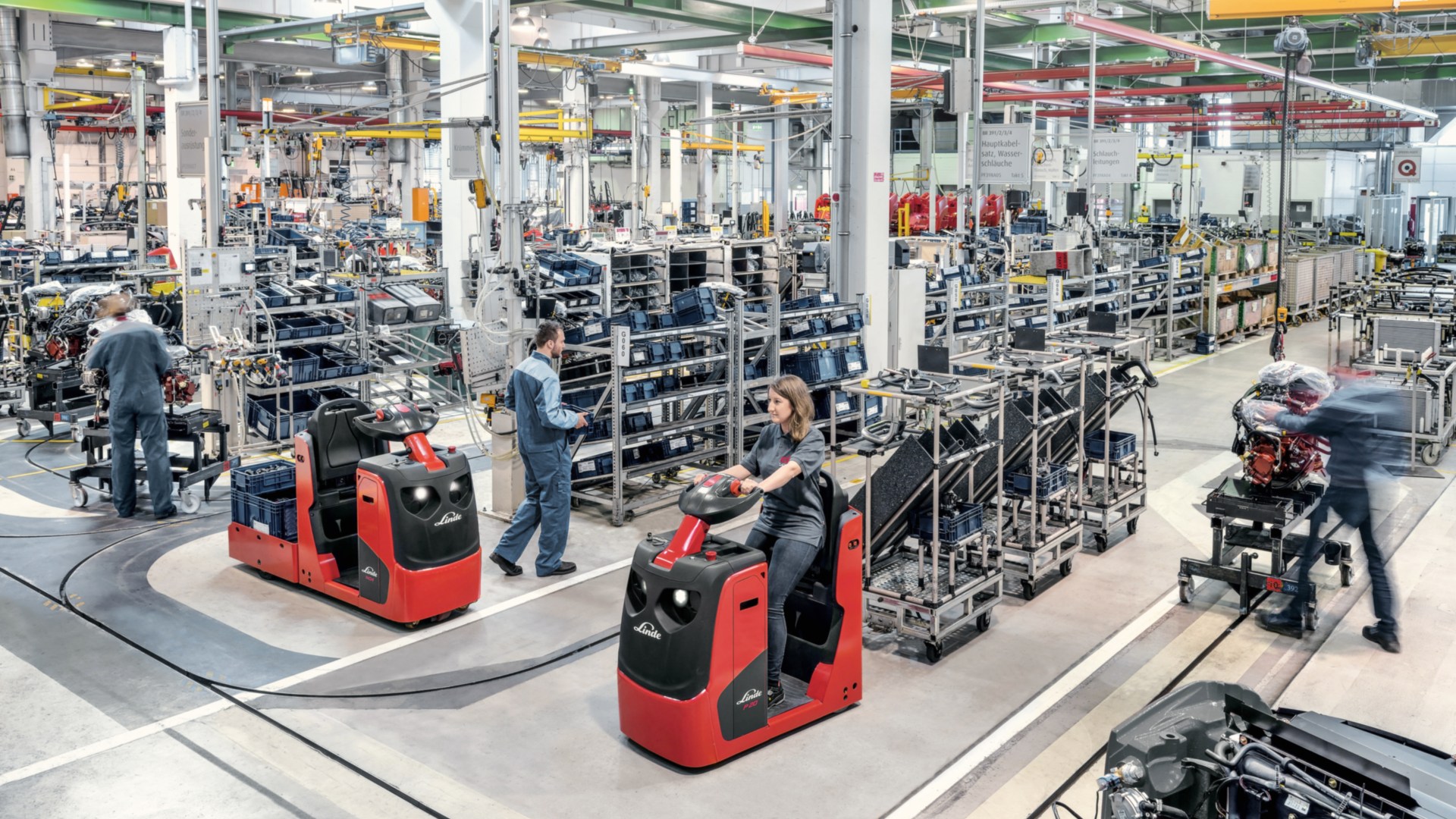 Tractores con varios soportes de mercancía transportan componentes a la línea de producción.
